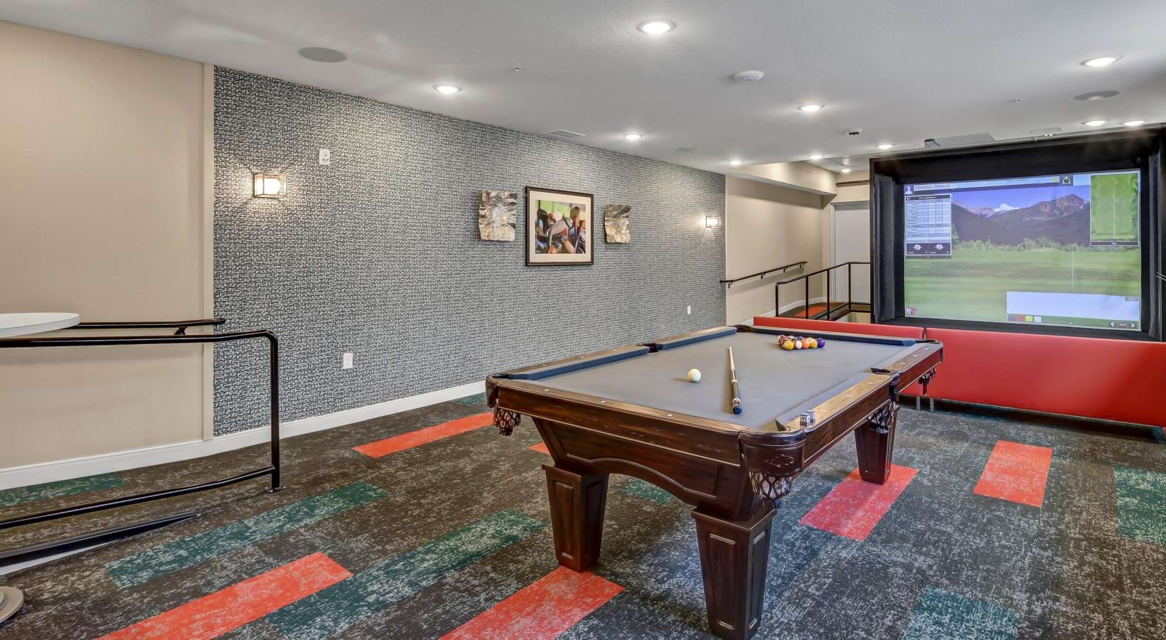 a room with a pool table and a golf simulator
