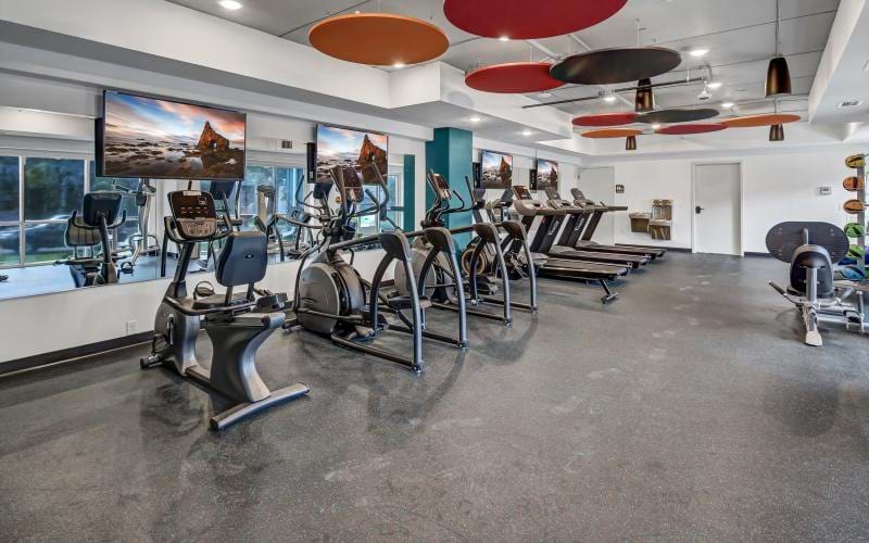 a gym with exercise equipment and tvs